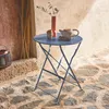 A small, round, folding bistro table set up on a stone patio with a vase and teapot on it. Anteprima dell’immagine prodotto