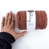 A hand is placed next to a roll of macrame cord. Podgląd zdjęcia produktu