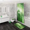 A modern bathroom with marble-effect tiles, a white vanity with a sink, a toilet, a bathtub, and a shower curtain with a green leaf and water drop design. A matching bath mat and toilet seat cover are also visible. Produktbild-Vorschau