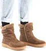 A pair of brown suede boots with fur trim, worn with cuffed jeans. Voir les images du produit