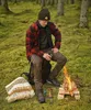 A person is sitting by a campfire in a forest setting. Produktbild-Vorschau