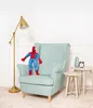 A Spiderman plush toy sits on a light blue armchair next to two small side tables, one with a vase and alarm clock. A floor lamp is to the left. Podgląd zdjęcia produktu