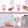 Collage of four images showing a pink bunny-shaped alarm clock and its features. Produktbild-Vorschau