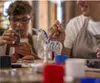 Two people are painting a unicorn figurine at a table. Anteprima dell’immagine prodotto