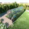 A greenhouse in a garden setting with a paved walkway. Produktbild-Vorschau
