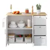 A white kitchen island with a wooden countertop, open doors revealing shelves with dishes and produce, and three drawers on the side. Podgląd zdjęcia produktu