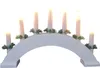 A white electric candle holder shaped like an arch, decorated with small green pine branches and holding seven white candles. Voir les images du produit