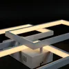 A close-up shot of a modern white LED ceiling light with a geometric design, against a black background. Náhled obrázku produktu
