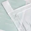 A close-up view of a white fabric curtain with a drawstring and a clear plastic toggle, layered over a light green background with text. Produktbild-Vorschau
