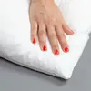 A hand pressing down on a white pillow. Produktbild-Vorschau
