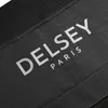 A close-up of a black fabric label with the brand name DELSEY and PARIS printed in white. Produktbild-Vorschau