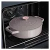 A gray cast iron pot with a rose gold handle sits on a rack inside a dark oven. Anteprima dell’immagine prodotto