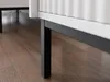 A close-up view of the legs and bottom edge of a white cabinet with a black metal frame, resting on a wooden floor. Náhľad obrázku produktu