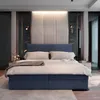 A modern bedroom with a large blue upholstered bed as the focal point. Produktbild-Vorschau