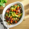 A close-up shot of a Villeroy & Boch Vapiano salad bowl filled with a colorful salad, placed on a wooden table. Voir les images du produit