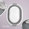 A top-down view of a collapsible laundry basket with clothes inside, placed on a light purple background. Produktbild-Vorschau