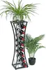 A black metal wine rack filled with wine bottles, topped with a potted plant. Another potted plant is to the right. Podgląd zdjęcia produktu