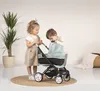 Two children playing with a doll stroller in a room. Produktbild-Vorschau