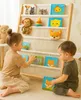 Two young children are playing with books on a wooden bookshelf. Anteprima dell’immagine prodotto