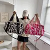 Two duffel bags are held up by a person in front of shelves. Produktbild-Vorschau