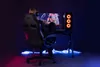 A person is playing a video game on a computer in a gaming chair, with neon lighting around the desk. Produktbild-Vorschau