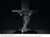 A black range hood is shown above a stovetop with a pot of food emitting steam. A diagram illustrates the hob-to-hood function. Voir les images du produit