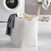 A laundry basket filled with clothes next to a washing machine. Náhľad obrázku produktu
