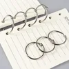 A close-up shot of several silver binder rings on a lined notebook. Produktbild-Vorschau