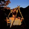 An outdoor dining setup at dusk, with a table set for a meal under a canopy of string lights. Voir les images du produit