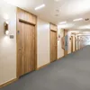 A long hotel corridor with multiple doors on the left and right sides, leading into the distance. Podgląd zdjęcia produktu