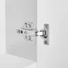 A close-up view of a cabinet hinge attached to a white cabinet door and frame. Produktbild-Vorschau