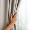 A hand is shown adjusting a light beige curtain, with a sheer curtain visible behind it. Produktbild-Vorschau