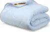 A folded light blue comforter with a gold brand tag visible. Podgląd zdjęcia produktu