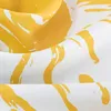 A close-up of fabric with a yellow abstract pattern on a white background. Produktbild-Vorschau
