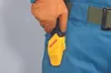 A gloved hand holds a yellow Tajima holster attached to a blue garment. Anteprima dell’immagine prodotto