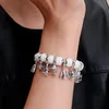 A close-up shot of a person's arm wearing a charm bracelet with multiple dangling charms. Voir les images du produit