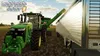 A tractor is unloading grain into a trailer in a field. Produktbild-Vorschau
