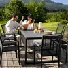A couple is enjoying a meal and working on a laptop at a table on a wooden deck with a scenic mountain view. Produktbild-Vorschau