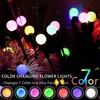 Close-up of colorful LED lights shaped like flowers, illuminating a dark garden setting. Produktbild-Vorschau