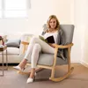 A woman is reading a book while sitting in a rocking chair in a living room. Podgląd zdjęcia produktu