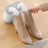 A person's hand is shown inserting a boot into a shoe dryer. Produktbild-Vorschau