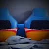 A close-up view of a child's bed with two blue headboards and colorful pillows. Anteprima dell’immagine prodotto