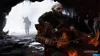 Kratos is in a cave, aiming a bow and arrow, with a shadowy figure in the background. Náhľad obrázku produktu