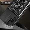 A close-up, angled shot of a black phone case with a ring stand and camera cover, shown in a dynamic pose as if falling and cracking the surface it's hitting. Produktbild-Vorschau