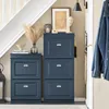 A hallway with a blue shoe cabinet, a staircase, and a denim jacket hanging on a hook. Voir les images du produit