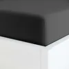 A close-up view of a black fitted sheet on a white bed frame. Produktbild-Vorschau