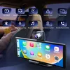 A car interior with a large screen display mounted on the dashboard, showing various app icons. Above the screen, there are several feature icons with German text. Produktbild-Vorschau