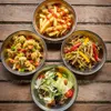 Four bowls of food arranged on a wooden table. Náhled obrázku produktu