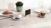 A table setting with a croissant, coffee, and a small chalkboard. Anteprima dell’immagine prodotto