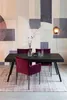 A dining table with chairs set in a room with a patterned wallpaper and a rug. Produktbild-Vorschau